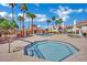 Community pool and hot tub surrounded by lounge chairs and palm trees on a sunny day at 605 Devonhall St # 202, Las Vegas, NV 89145