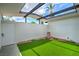 Charming backyard area featuring green turf, white brick walls and black support beams at 6320 Dayton Ave, Las Vegas, NV 89107