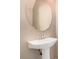 A pedestal sink and round mirror complete this cozy powder room at 6620 Tulip Falls Dr, Henderson, NV 89011