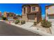 Tan two-story home with a garage, neat landscaping, and a blue sky at 6620 Tulip Falls Dr, Henderson, NV 89011