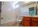Bright bathroom featuring a tub-shower combo, tile surround, and wood vanity at 708 Canyon Country Cir, Henderson, NV 89002