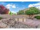 Backyard featuring spa area with rock accents, desert landscaping, and mature trees for added privacy at 7183 Majestic Bluff Pl, Las Vegas, NV 89113