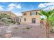 Backyard showing the two-story home with mature palm tree, dining space on a concrete patio, and gravel landscape at 7183 Majestic Bluff Pl, Las Vegas, NV 89113