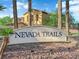Nevada Trails community entrance sign flanked by palm trees against a backdrop of luxury homes and blue sky at 7183 Majestic Bluff Pl, Las Vegas, NV 89113