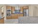 Close-up of a kitchen with stainless appliances, and a view of the breakfast bar and a stainless steel range hood at 7183 Majestic Bluff Pl, Las Vegas, NV 89113