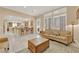 Bright living room with tan sofas, a decorative rug, and access to the kitchen and dining area at 7183 Majestic Bluff Pl, Las Vegas, NV 89113