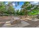 Community park featuring concrete picnic tables, surrounded by mature trees and gravel landscaping at 7183 Majestic Bluff Pl, Las Vegas, NV 89113