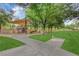 Community playground with a sunshade, walking path, seating, mature trees, and grassy areas at 7183 Majestic Bluff Pl, Las Vegas, NV 89113