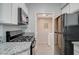 Modern kitchen featuring white cabinets, granite countertops, gas range, and access to the laundry room at 7189 S Durango Dr # 208, Las Vegas, NV 89113