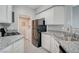 Modern kitchen with white cabinets, granite countertops, stainless steel sink, and access to the laundry room at 7189 S Durango Dr # 208, Las Vegas, NV 89113