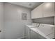 This laundry room includes a washer, dryer, and overhead storage cabinets at 7189 S Durango Dr # 208, Las Vegas, NV 89113