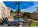 Comfortable backyard setting with an umbrella-covered dining table and well-maintained artificial turf at 7912 Horn Beam Ct, Las Vegas, NV 89131