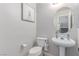 Cozy half-bathroom with a pedestal sink, toilet, and decorative mirror at 7912 Horn Beam Ct, Las Vegas, NV 89131