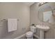 A tidy half bathroom featuring a pedestal sink, round mirror and neutral color palette at 8255 S Las Vegas Blvd # 2004, Las Vegas, NV 89123