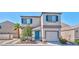 Charming two-story home featuring a stucco facade, attached garage, blue shutters, and manicured landscaping at 9979 Keephills St, Las Vegas, NV 89183