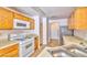 Galley kitchen featuring oak cabinets, laminate countertops, white appliances and vinyl flooring at 9979 Keephills St, Las Vegas, NV 89183