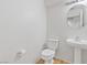 Bright bathroom with a pedestal sink, updated lighting, and a toilet with a wooden floor at 10638 Pueblo Springs St, Las Vegas, NV 89183