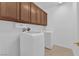 Well-equipped laundry room features a modern washer and dryer, accompanied by functional upper cabinets for storage at 11237 Newbury Hills Ave, Las Vegas, NV 89138
