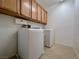 Well-lit laundry room features tile flooring, cabinetry, and modern side-by-side washer and dryer at 11237 Newbury Hills Ave, Las Vegas, NV 89138
