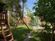 Lush backyard featuring a playset, trees, and green lawn with a brick pathway, ideal for outdoor fun at 1800 Quail Point Ct, Las Vegas, NV 89117