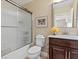 Bathroom with framed corgi art and vanity area, with a glass door shower, toilet, and tan paint at 2400 Trissino Ct, Henderson, NV 89044