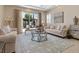 Cozy living room boasts stylish seating, a glass-top coffee table, and natural light from a sliding glass door at 2400 Trissino Ct, Henderson, NV 89044