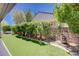 Backyard with artificial turf, stone fountain, stone wall and lush greenery at 2545 Nashira St, Henderson, NV 89044