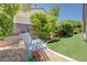 Landscaped backyard featuring an ornate bench seating area with fresh flowers at 2545 Nashira St, Henderson, NV 89044