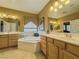Well-lit bathroom featuring double sinks, large mirrors, soaking tub and neutral color palette at 3476 Ridge Meadow St, Las Vegas, NV 89135