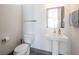 A minimalist bathroom featuring a pedestal sink, a framed mirror, and a contemporary toilet at 4070 N Tee Pee Ln, Las Vegas, NV 89129