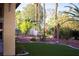Lush backyard with artificial turf, mature palms, and a privacy wall, perfect for relaxing outdoors at 4554 Blue Mesa Way, Las Vegas, NV 89129