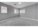 This bedroom features neutral gray carpeting and gray walls with baseboard trim and three windows at 484 Merseyside Dr, Las Vegas, NV 89178