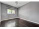 Bright bedroom with hardwood floors, large window providing natural light, ceiling fan, and neutral gray walls at 484 Merseyside Dr, Las Vegas, NV 89178