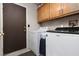 Functional laundry room with washer, dryer, storage cabinets, and access door at 5260 Styers St, North Las Vegas, NV 89031