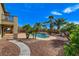 Lush backyard with a sparkling pool, spa, palm trees, landscaping, and covered patio at 5949 Casa Coronado Ave, Las Vegas, NV 89131
