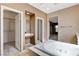 A relaxing bathroom featuring a soaking tub, vanity, tile floors and an adjacent walk-in closet at 5949 Casa Coronado Ave, Las Vegas, NV 89131