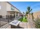Landscaped backyard with patio, fire pit, artificial turf, outdoor seating, and privacy fencing at 6141 Annville Ct, North Las Vegas, NV 89081