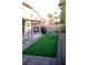 Backyard with artificial grass features covered patio with barbeque and outdoor seating area at 6141 Annville Ct, North Las Vegas, NV 89081