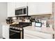 Modern kitchen featuring stainless steel appliances, white cabinetry, granite countertops, and brick backsplash at 6228 Haiku Stairs St, Las Vegas, NV 89148