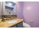 Cozy bathroom featuring a granite countertop, mosaic backsplash, and a decorative mirror at 6655 Flaminian Ln # 104, North Las Vegas, NV 89084