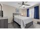 Neutral bedroom with a ceiling fan, window with blue curtains, bed, and a dresser at 6857 Stone Tower Ct, Las Vegas, NV 89149