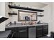 Entertaining wet bar area featuring granite countertops, dark cabinetry, mirrored backsplash, and shelving at 6857 Stone Tower Ct, Las Vegas, NV 89149
