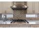 Modern kitchen featuring stainless steel hood, gas range, light cabinets, and mosaic backsplash at 7112 Rancho De Taos Ct, Las Vegas, NV 89130