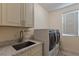 Well-equipped laundry room with sink, cabinet, and modern washer and dryer at 7112 Rancho De Taos Ct, Las Vegas, NV 89130
