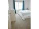 Bright bedroom features a window with blue curtains, a white bedspread, light carpet, and a white dresser at 7342 N Decatur Blvd # 5, Las Vegas, NV 89131