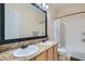 Bathroom with double sinks, granite counters, framed mirror, and shower with a tub at 7404 Eggshell Dr, North Las Vegas, NV 89084