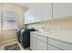 Well-lit laundry room with washer, dryer, sink, white countertops, and ample cabinet space at 7404 Eggshell Dr, North Las Vegas, NV 89084