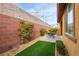 Charming backyard with brick wall, artificial turf, and quaint patio seating area at 7611 Redcloud Peak St St, Las Vegas, NV 89166