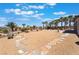 Desert-style backyard featuring decorative rock, palm trees, and a stone walkway leading to outdoor seating at 8536 Grand Palms Cir, Las Vegas, NV 89131