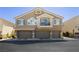 Exterior view of a multi-story home with garages and neutral color scheme at 10010 Aspen Rose St # 102, Las Vegas, NV 89183